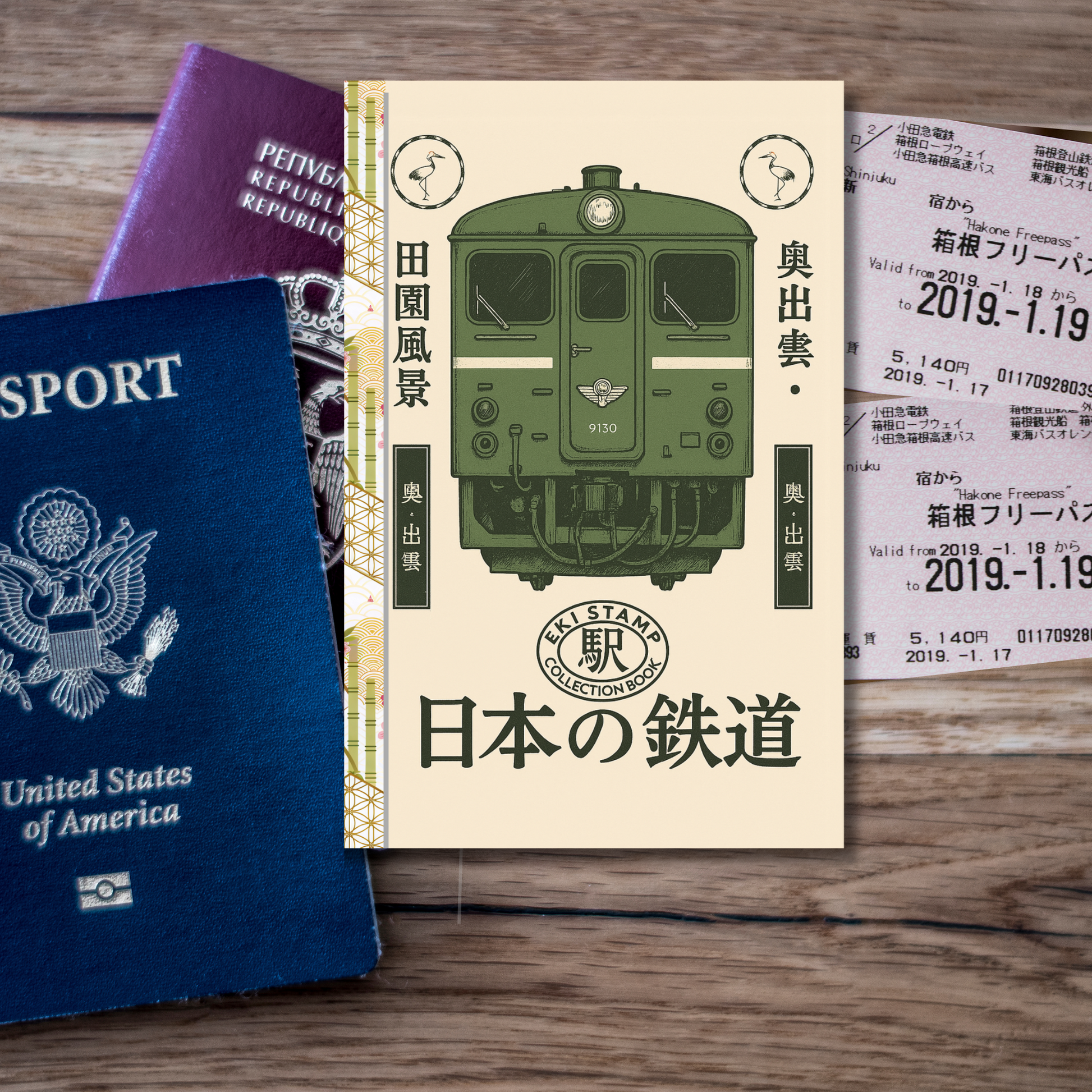 Passport, book with green train illustration, and Japanese text on a wooden surface