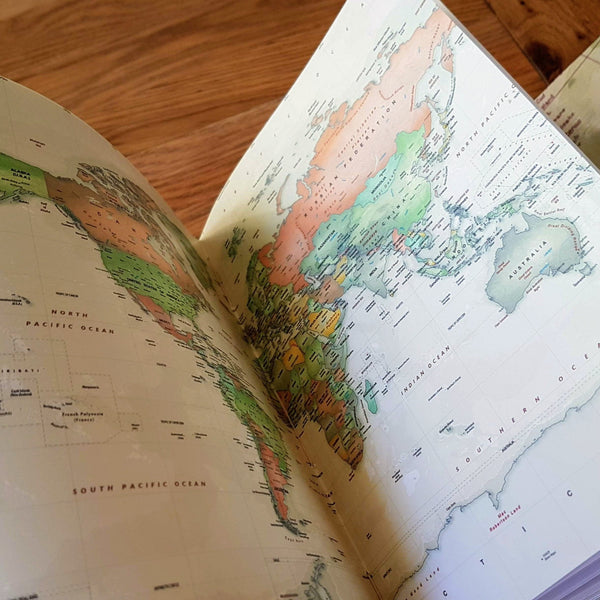 Centre spread of coloured world map inside a personalised leather travel journal