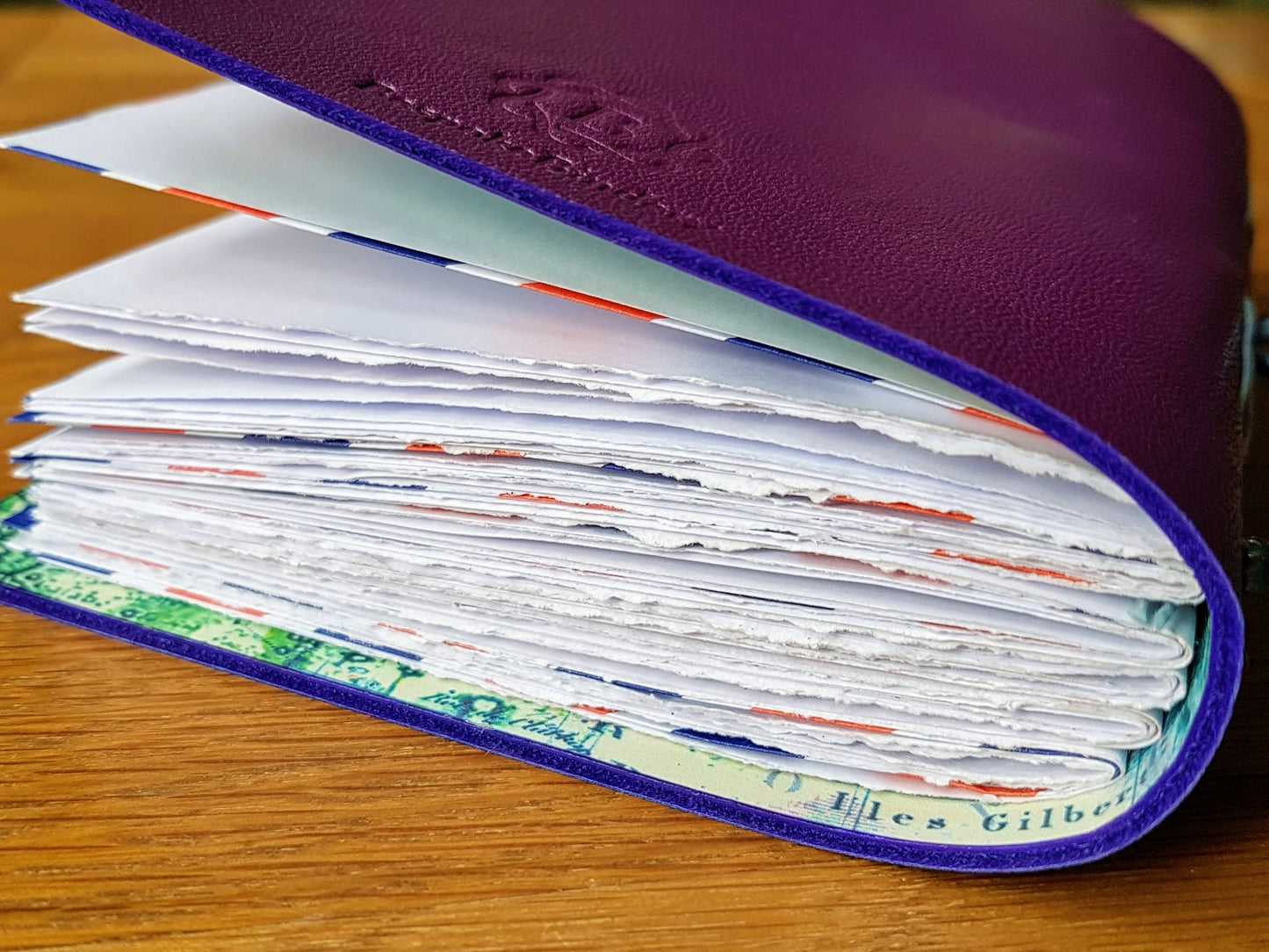 Purple leather travel journal showing hand torn paper pages and envelope pockets
