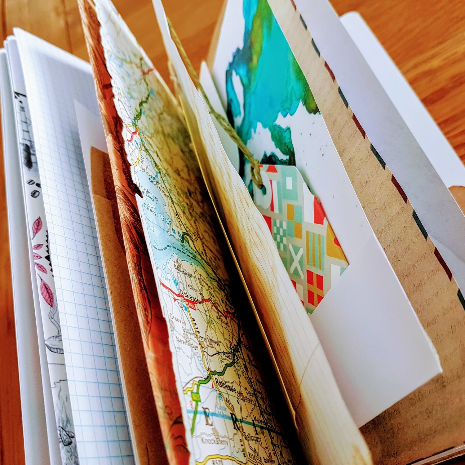 mixed paper pages inside starter junk journal showing maps and tags