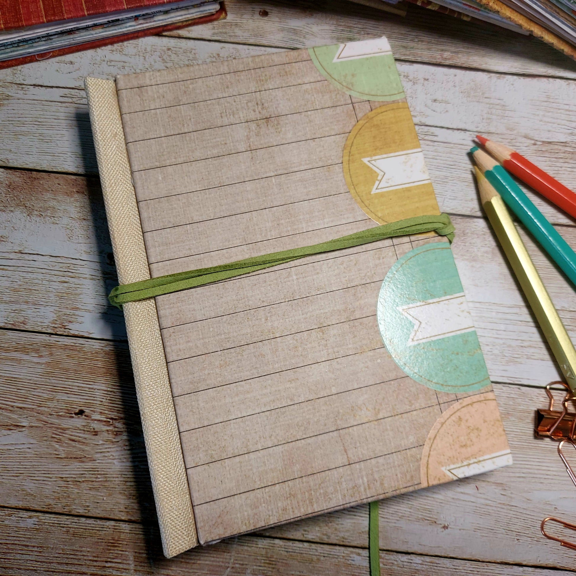 Notebook with decorative封皮 on a wooden surface with pencils