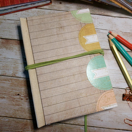 Notebook with decorative封皮 on a wooden surface with pencils