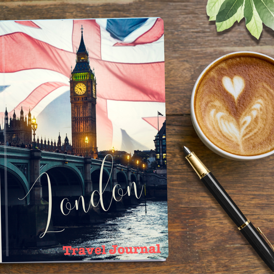 London Travel Journal showing London Bridge, river Thames and Big Ben at night time with a UK union jack flag in the background.  On a table with a cup of coffee and pen