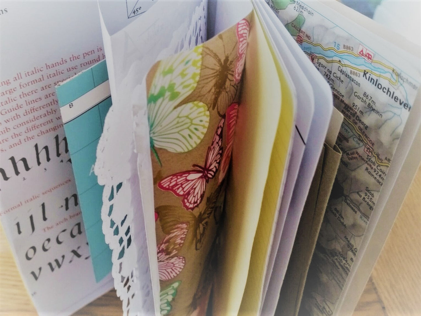 Mixed paper pages include calligraphy, lace doily, maps and other journaling and scrapbooking items