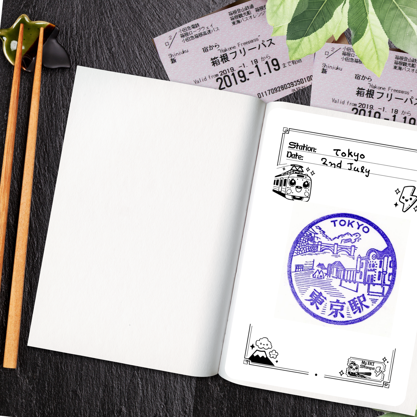 Open notebook with Tokyo railway station travel stamps and tickets on a dark surface