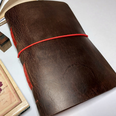 waxed brown leather journal with red elastic and stitching