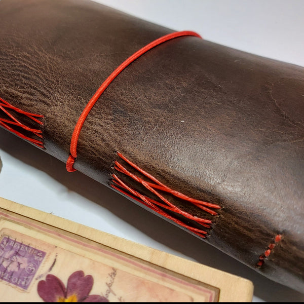side view of the journal showing red french link stitch binding and red elastic loop