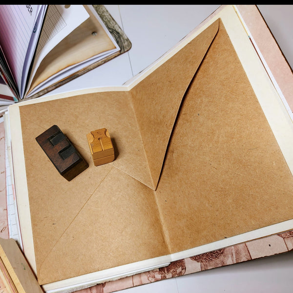 open spread showing large brown kraft paper envelope as storage pocket inside mixed paper journal