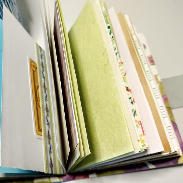 an open mixed paper journal with pages fanned out to show different designs of paper