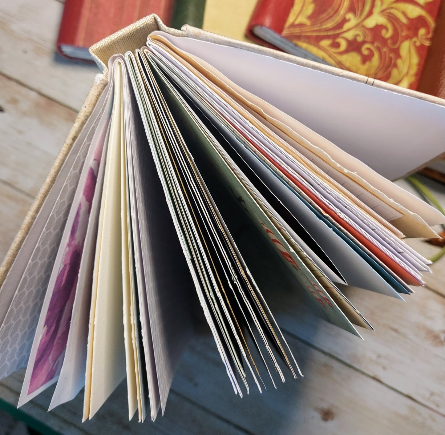 Open  junk journal mixed paper notebook with colorful pages on a wooden surface