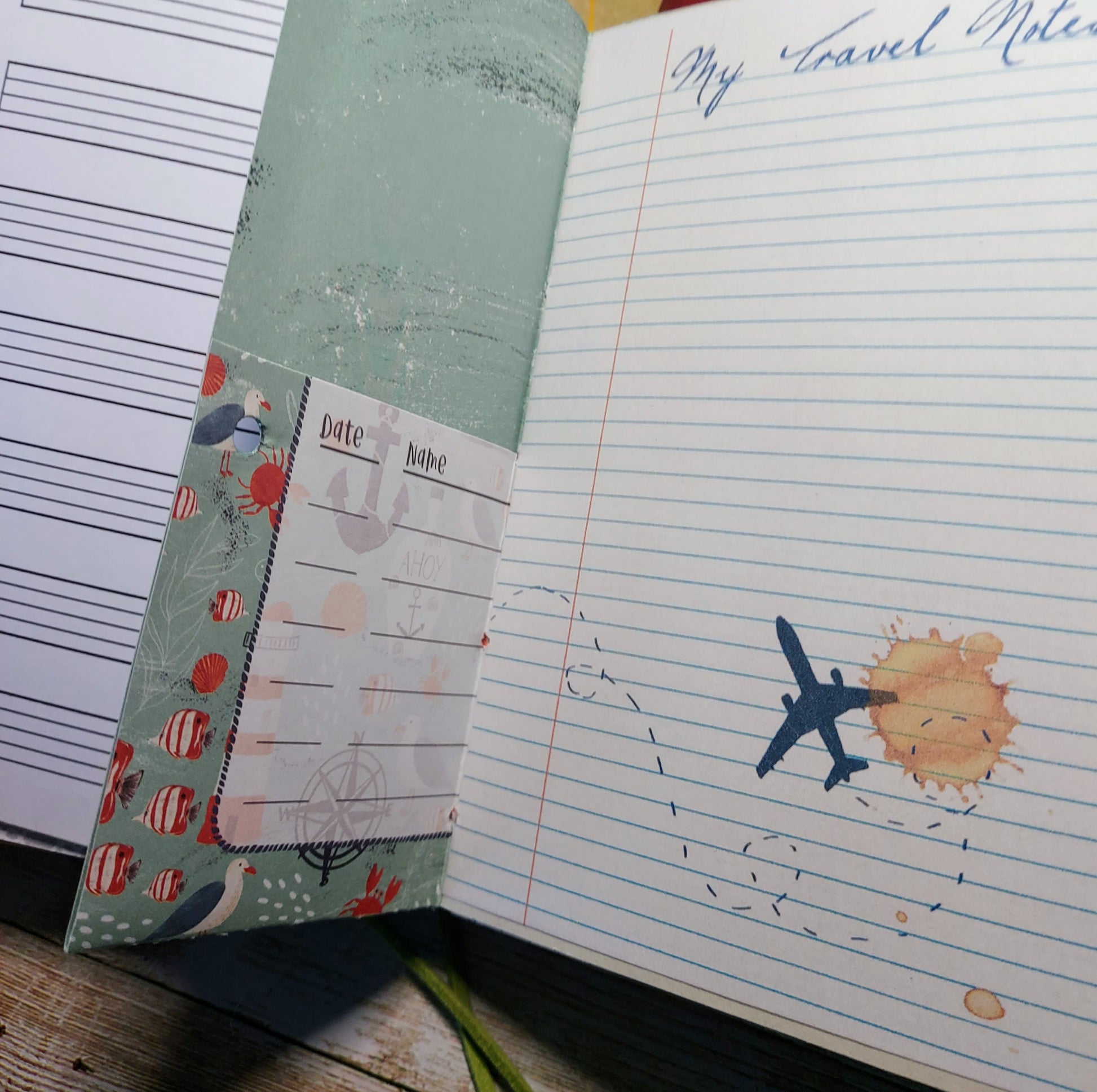 Notebook with airplane and sun illustration on lined paper, next to a green cover with decorative elements.