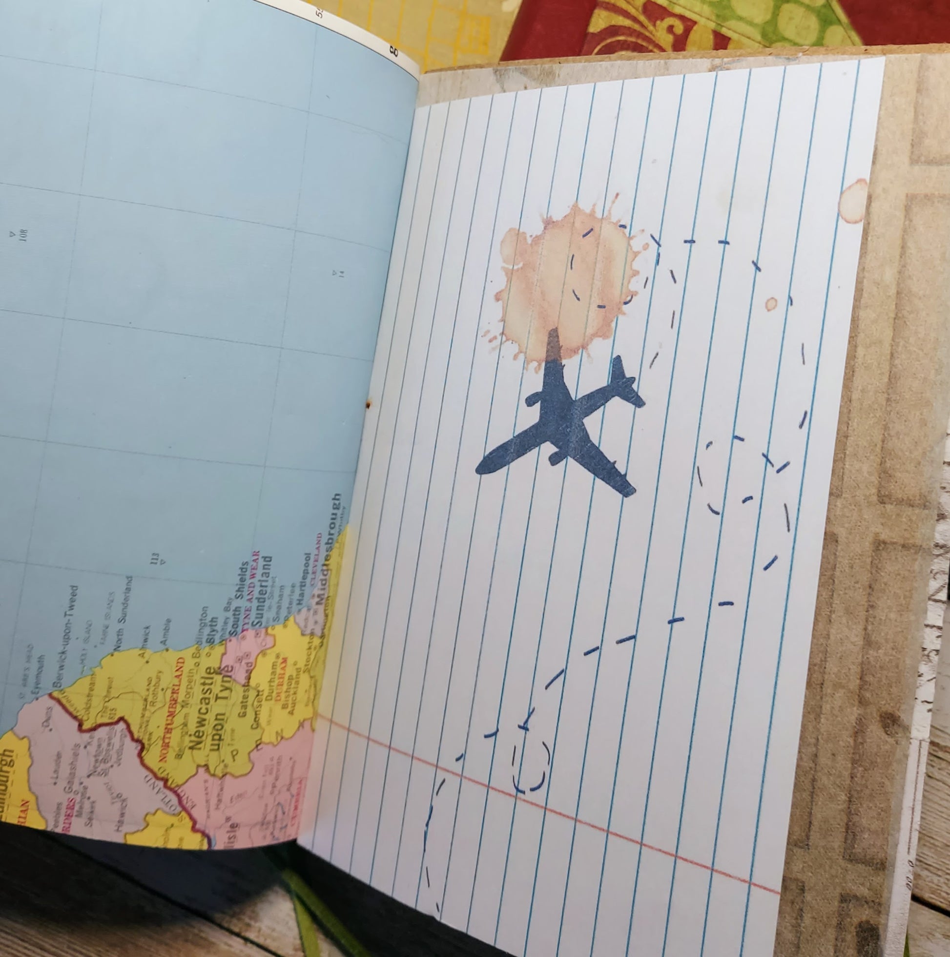 Open book with a drawing of an airplane under a sun, on a wooden surface.