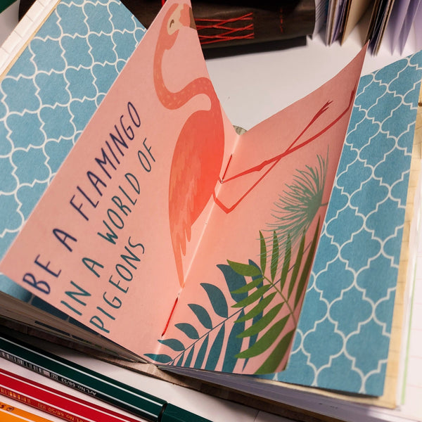 be a flamingo quote inside assorted pages of a mixed paper junk journal notebook