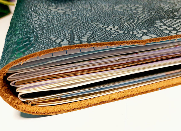end view of petrol blue mixed paper notebook showing thickness of genuine leather and assorted paper pages