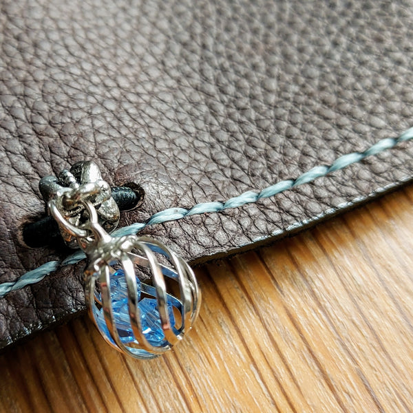 close up showing stitching and decorative bead attached to Dark Brown Leather Travelers Notebook
