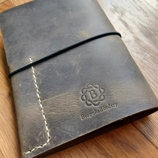rear view of hand stitched leather hunting shooting journal in waxed leather showing Bespoke Bindery logo