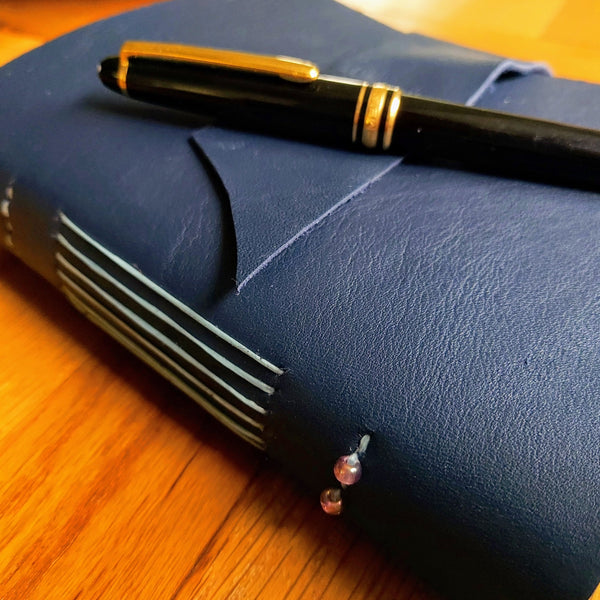 Dark Blue Leather Travel Journal with Mont Blanc Pen showing hand stitched spine with 2 decorative beads