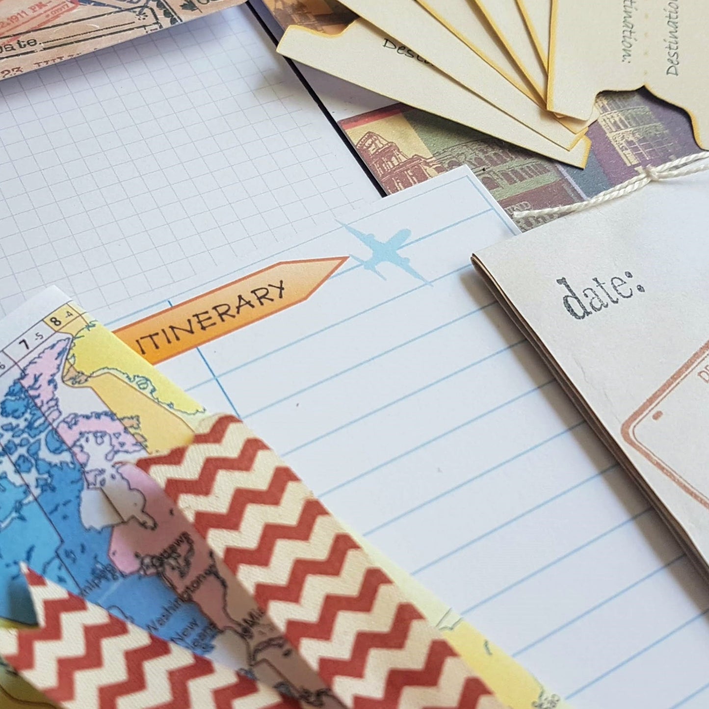 close up of mixed travel extras showing hand made booklet and zig zag paper clip