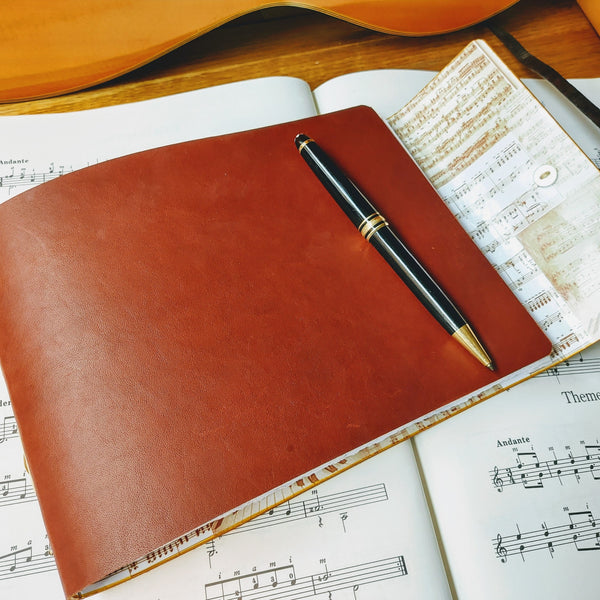 brown leather stave notation book with sheet music lining and mont blanc pen