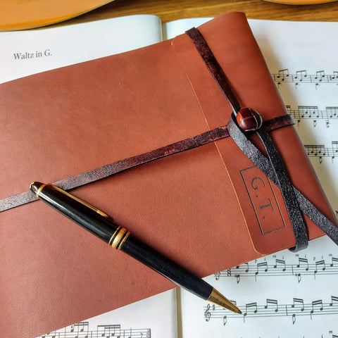 leather trifold music stave journal with leather strap and button fastening, mont blanc pen and sheet music