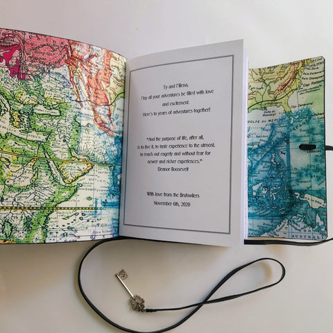 Open spread of the interior to a personalised leather travel journal.  Abstract map lining and personalised title page.  leather cord trimmed with a small silver key to fasten