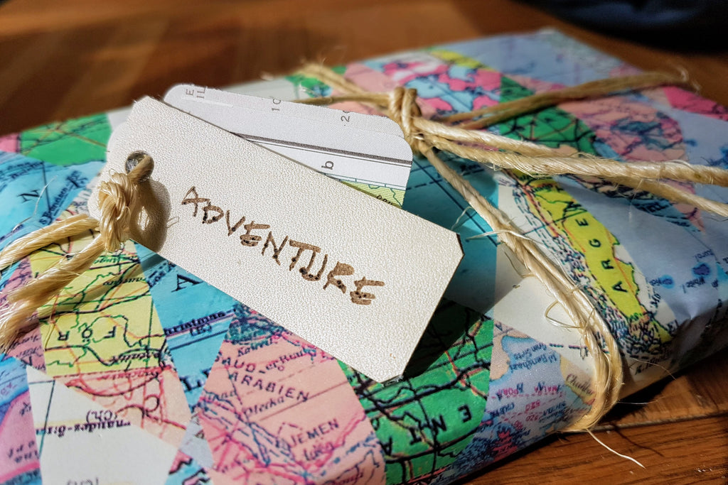 Add gift wrap with map themed wrapping paper, tied with twine and trimmed with leather tag saying Adventure